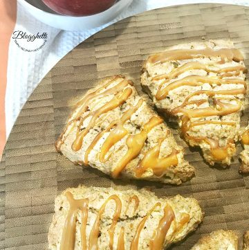 Caramel Apple Scones on a wooden platter with bowl of apples in the background