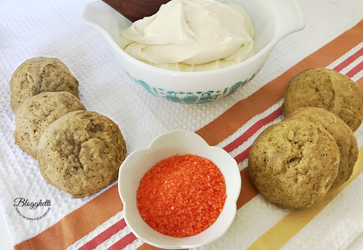 Pumpkin Cookies with bowl of homemade cream cheese frosting and orange sugar sprinkles