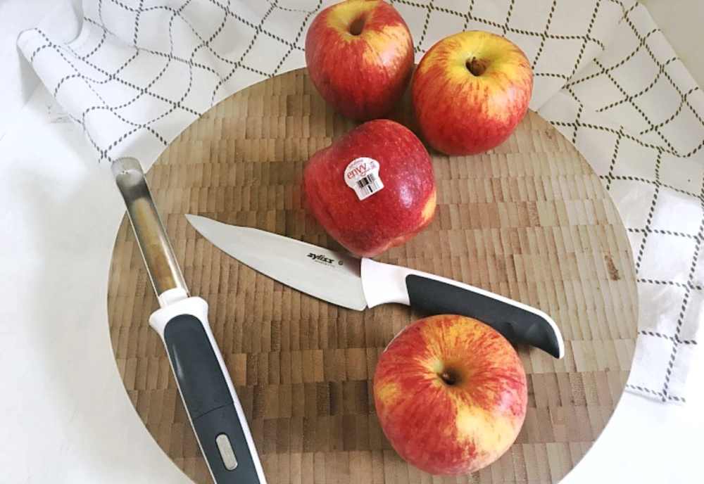 apples on cutting board with apple corer and knife