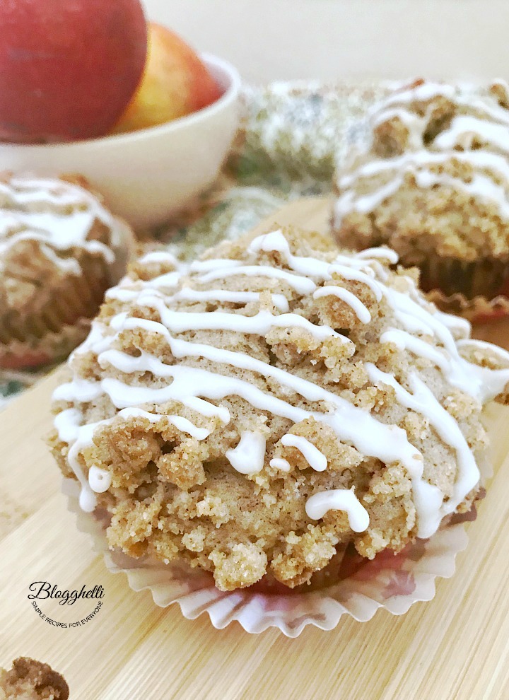 closeup of an Apple Coffee Cake Muffin with a bowl of apples in the background