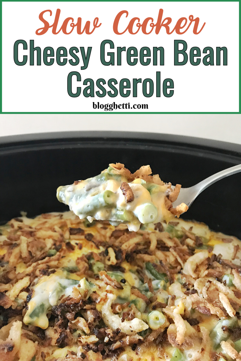 Close-up image of a slow cooker filled with cheesy green bean casserole topped with crispy fried onions. A spoon lifts a portion, showing tender green beans coated in a creamy, melted cheese. Text overlay at the top reads: "Slow Cooker Cheesy Green Bean Casserole