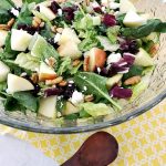 Apple Cranberry Pecan Salad in crystal bowl with a small wooden spoon