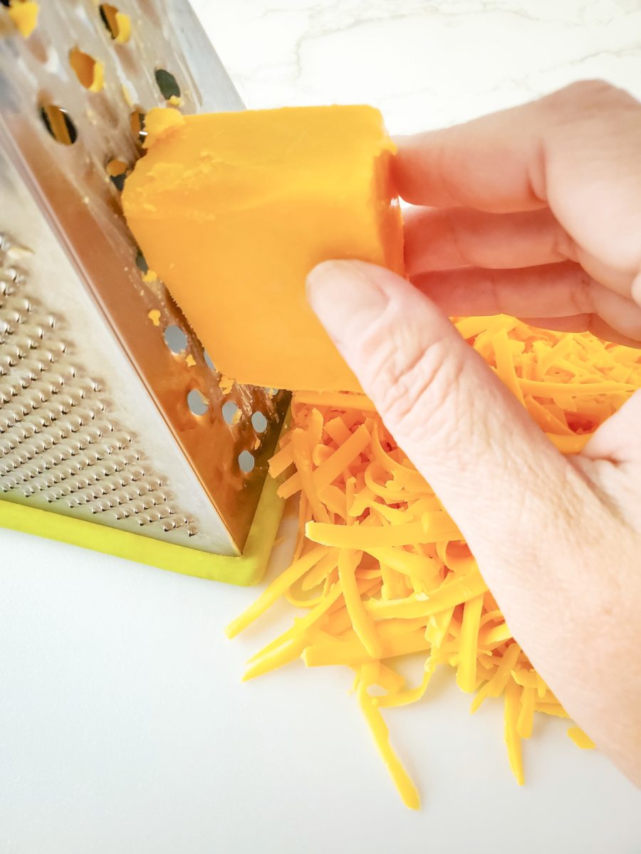 grating cheddar cheese with a box grater