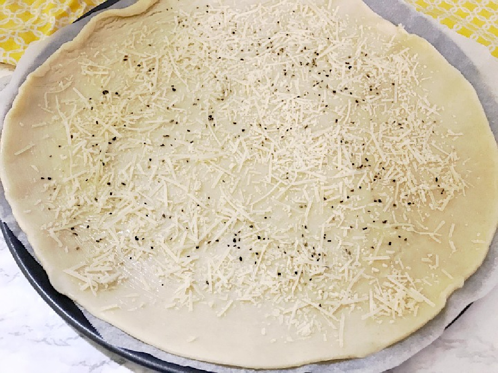 adding cheese and pepper to pie crust