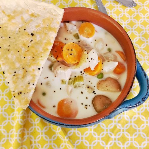 close up of bowl of chicken pot pie soup and pie crust wedge