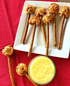 plate of mini cinnamon rolls on pretzel stick and a bowl of cinnamon roll dip