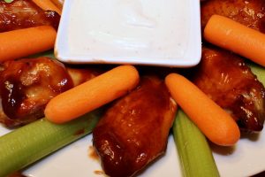 plate of smoked Coca Cola BBQ wings with carrot and celery sticks