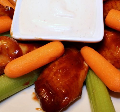 plate of smoked Coca Cola BBQ wings with carrot and celery sticks