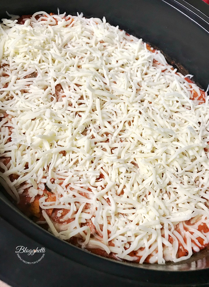 adding the cheese layer to the slow cooker baked ziti
