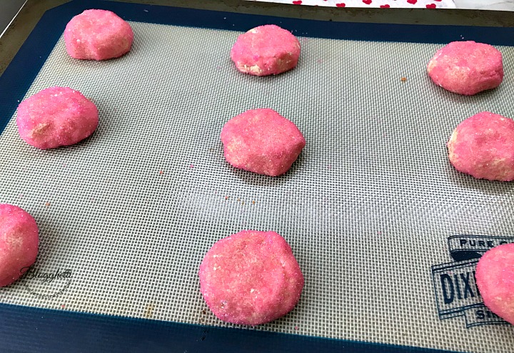 Pink crinkle cookie dough on baking sheet