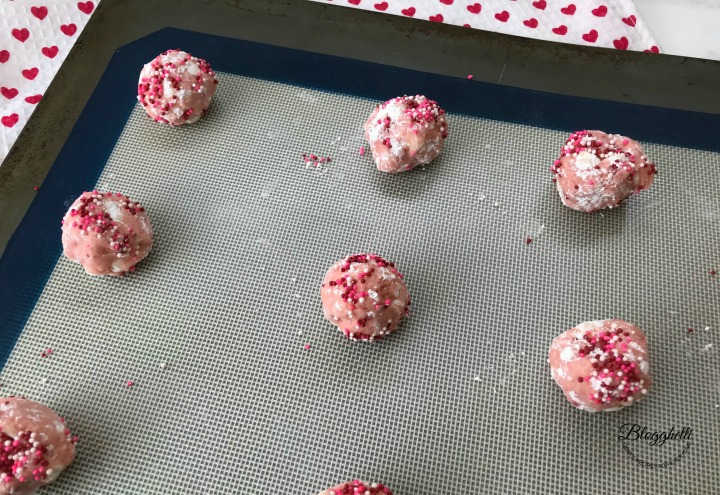 cookie dough balls rolled in sprinkles on baking sheet