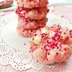 strawberry cheesecake cookies with white chocolate stacked on a white doily