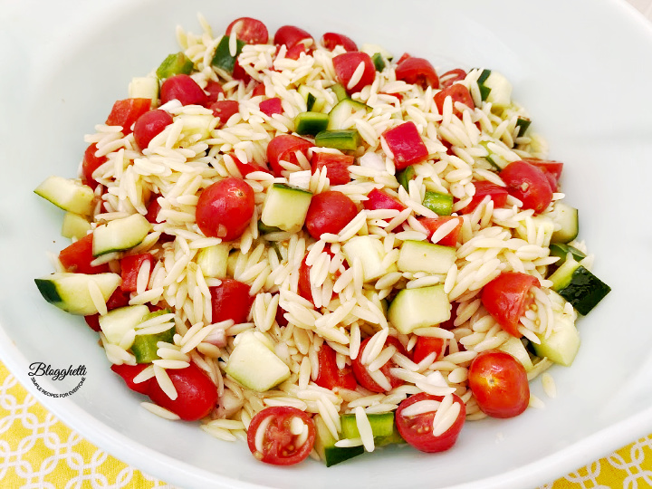mixing orzo pasta salad with dressing