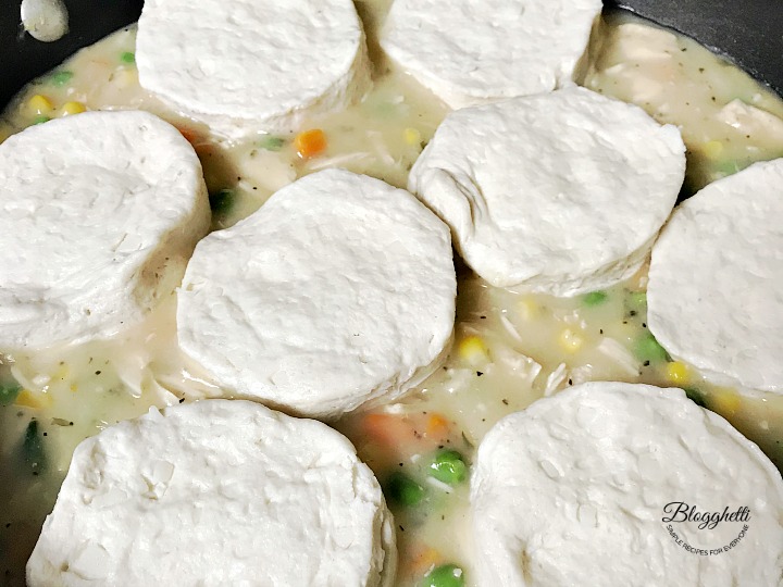 topping the pot pie mixture with biscuits