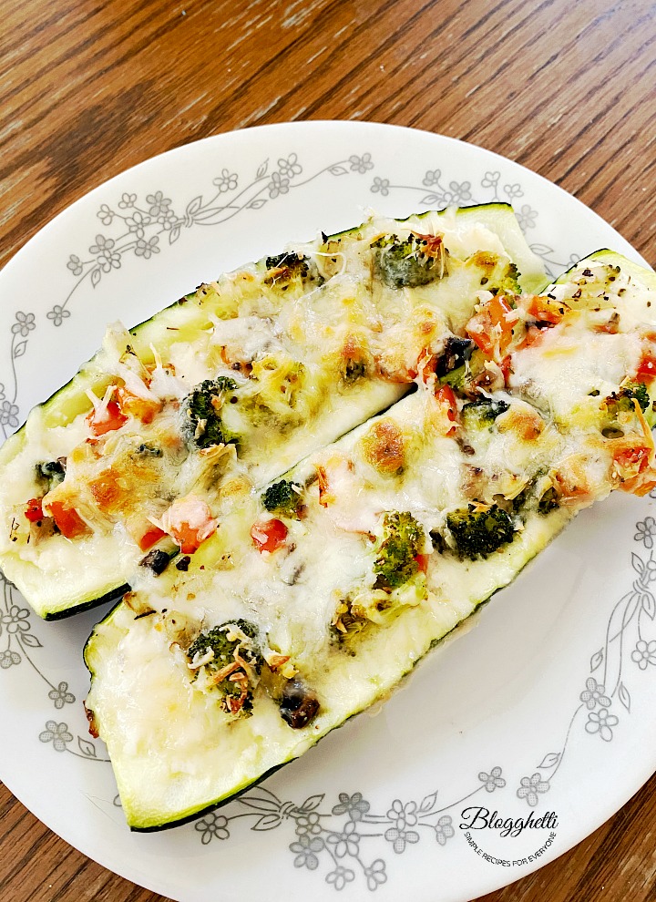 Three cheese stuffed zucchini with veggies on a while plate