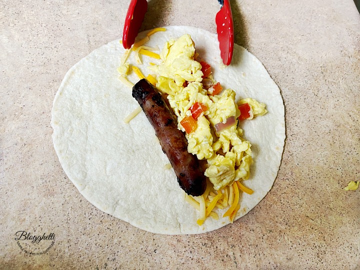 filling the tortilla shells with eggs and sausage