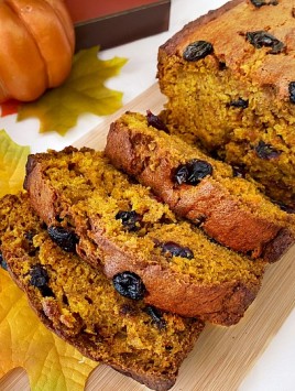Slices of pumpkin cranberry bread on wooden board with fall decor