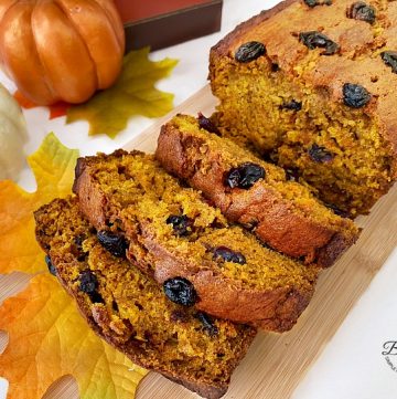Slices of pumpkin cranberry bread on wooden board with fall decor