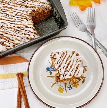 baked pumpkin cake with icing on beige plate with cake pan in background