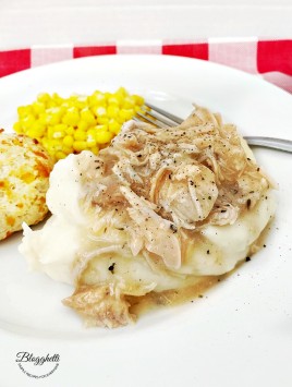 chicken and gravy with mashed potatoes, corn and cheese biscuit on white plate