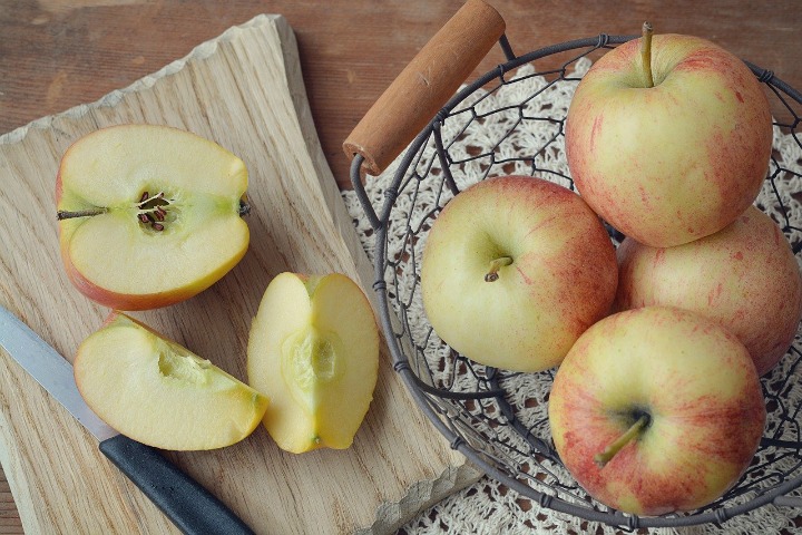 cutting board with cut apples and basket of apples