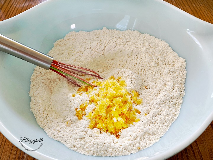 dry ingredients with lemon sugar in bowl with whisk
