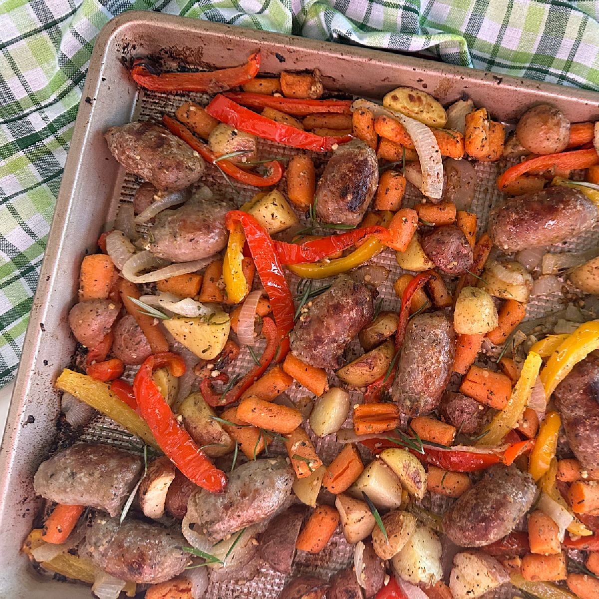 An overhead shot of a sheet pan filled with perfectly roasted Italian sausage, peppers, carrots, and potatoes, ready to serve.