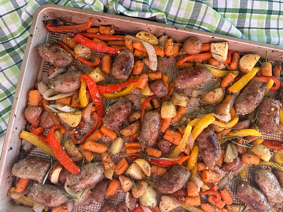 Close-up overhead view of the roasted Italian sausage and vegetable one-pan meal on a baking sheet.