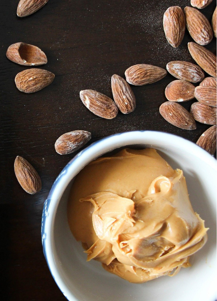 small bowl of almond butter with whole almond in background