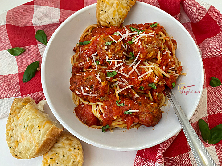 best spaghetti and meatballs in white bowl with garlic bread