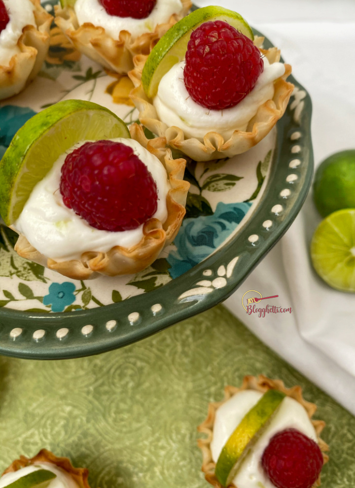 close up of key lime mini tarts with raspberry garnish