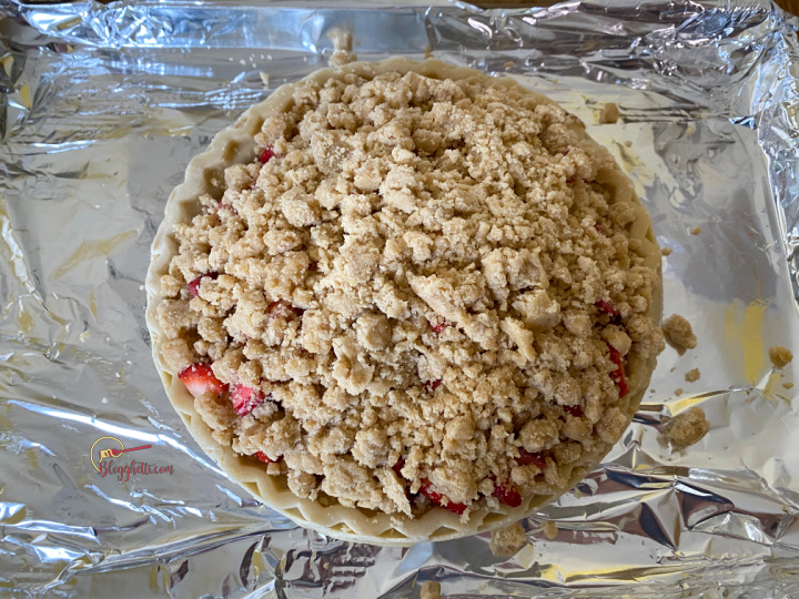 crumb topping on strawberry-rhubarb pie ready to bake
