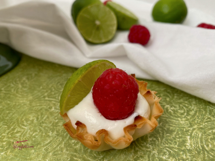 single key lime mini tart with raspberry garnish