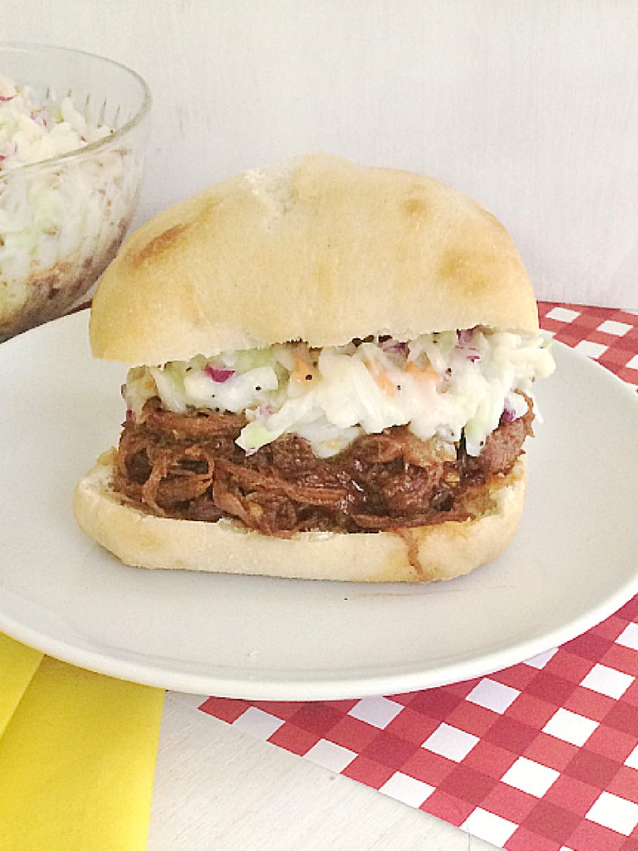 bbq beef and coleslaw on bun on white plate