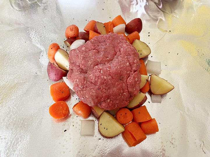 ground beef patty with veggies on aluminum foil
