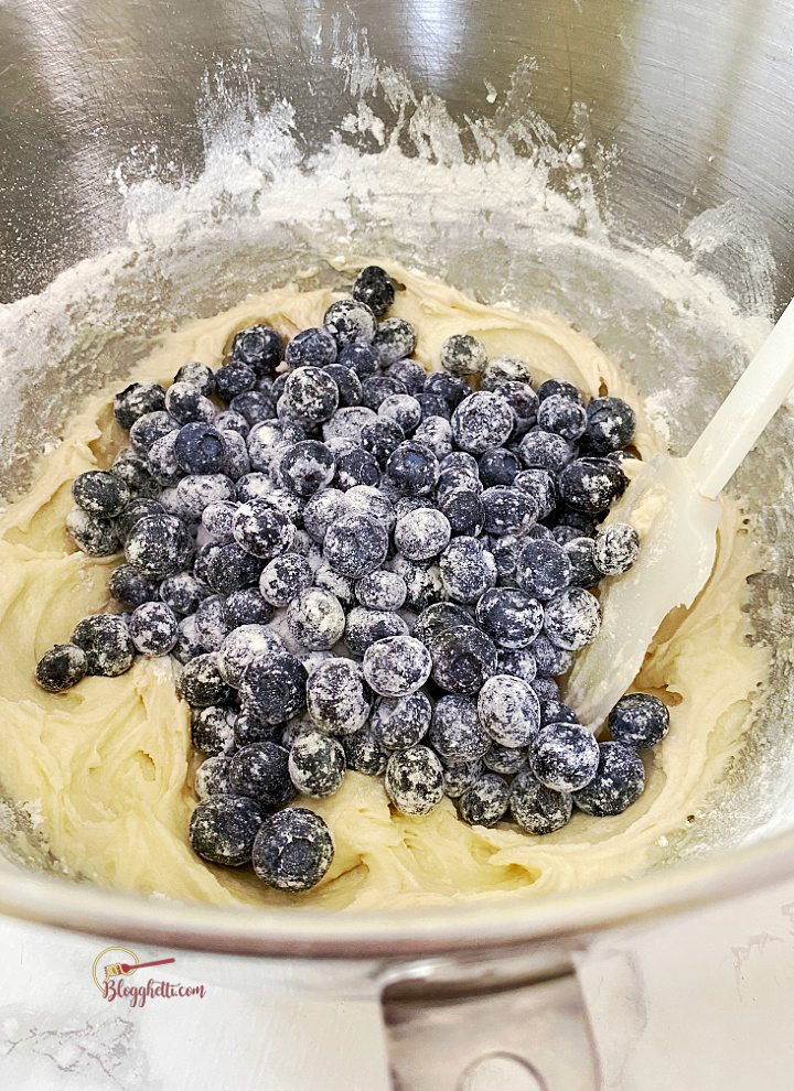 adding blueberries to cake batter in bowl