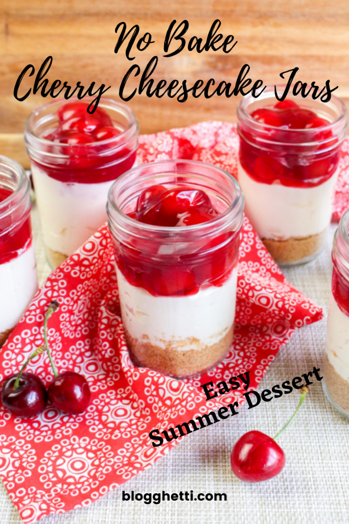 No Bake Cherry Cheesecakes in mason jars sitting on a red printed cloth