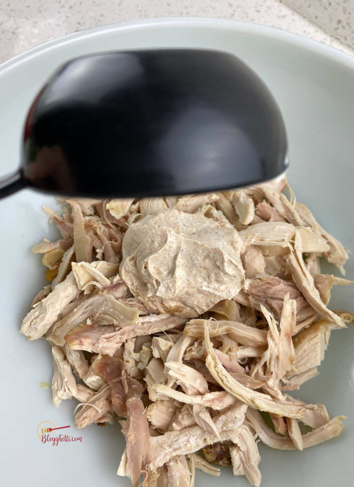 mixing shredded chicken with the sour cream mixture