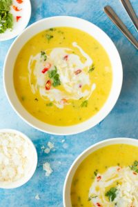 close up of creamy squash soup with garnishes in white bowl