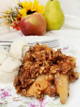 pear apple crisp with ice cream on plate and fruit in background