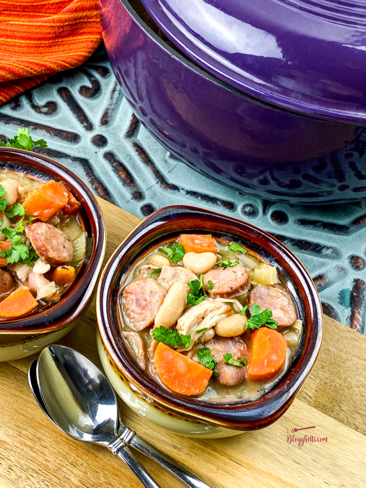 rustic chicken stew with white beans in bowl with cooking pot in background