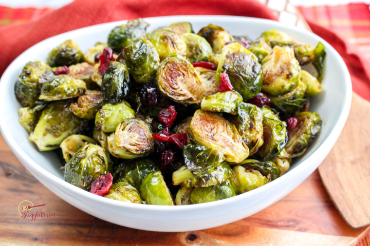 roasted balsamic brussel sprouts in white serving bowl on wooden platter