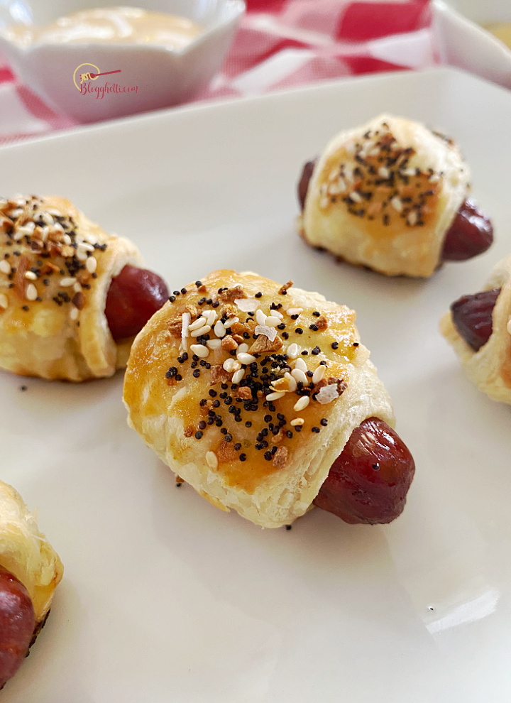 close of everything seasoning mini sausages wrapped in puff pastry on white tray