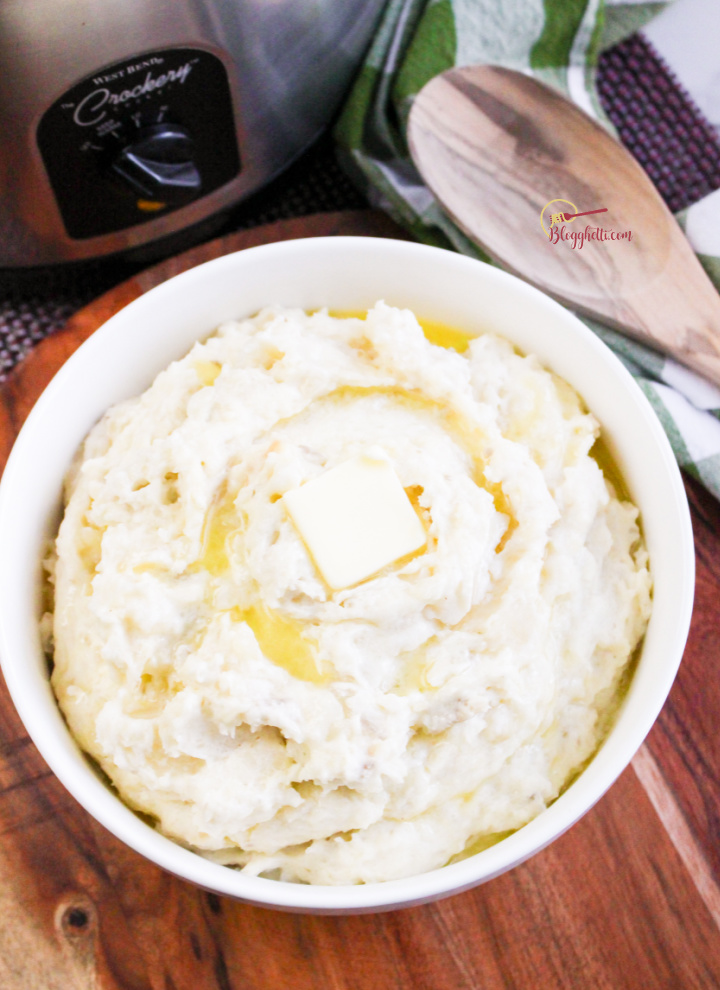 Slow Cooker Mashed Potatoes in white bowl with slow cooker in background