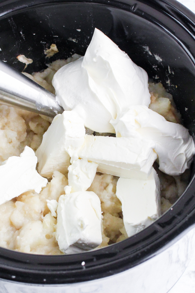 adding cream cheese to mashed potatoes in slow cooker