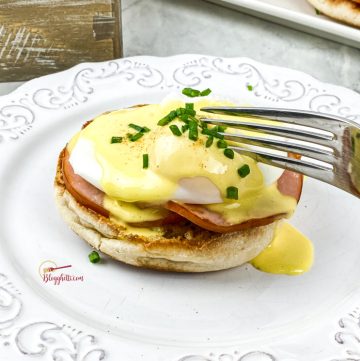 close up of eggs benedict with fork cutting into it