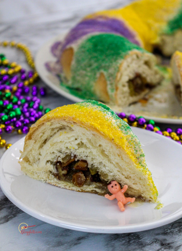 king cake slice on white plate showing the raising filling and little plastic baby