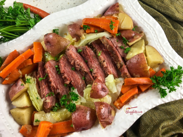 corned beef, cabbage, carrots, and potatoes on white serving platter