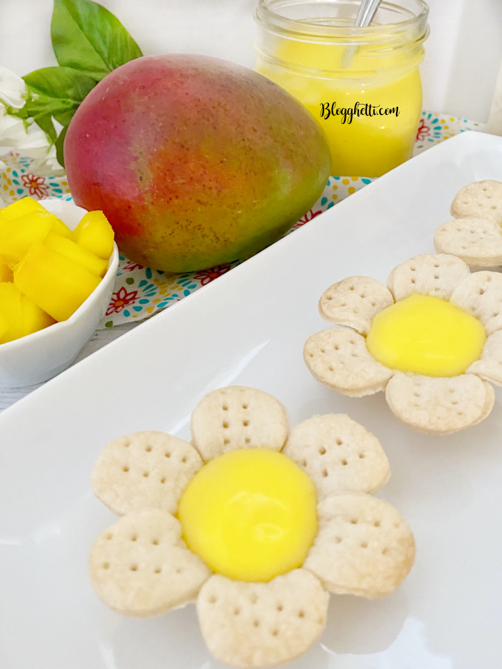 close up of mini mango tarts with fruit in background