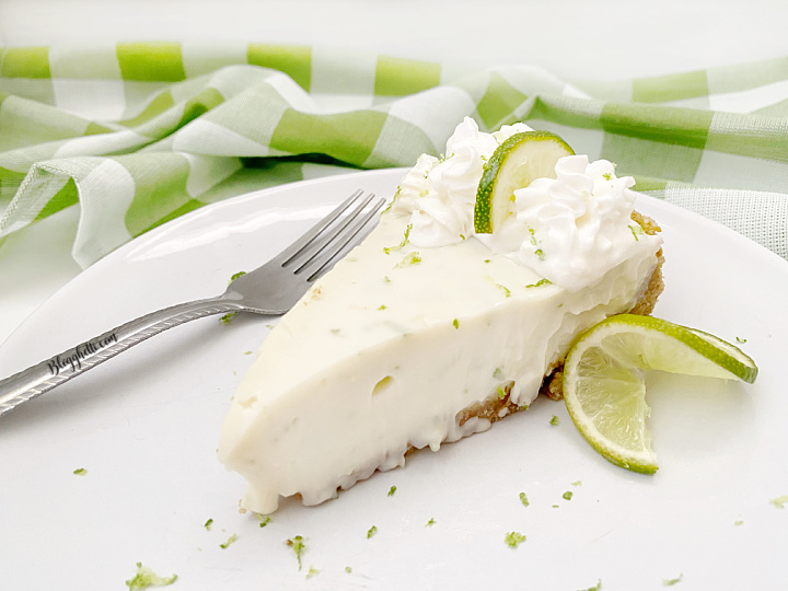 close up of slice of key lime pie on white plate with fork
